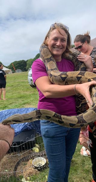 A woman is holding a large snake in her arms.