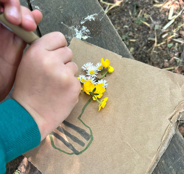 A person is kneeling down in a garden holding a shovel.
