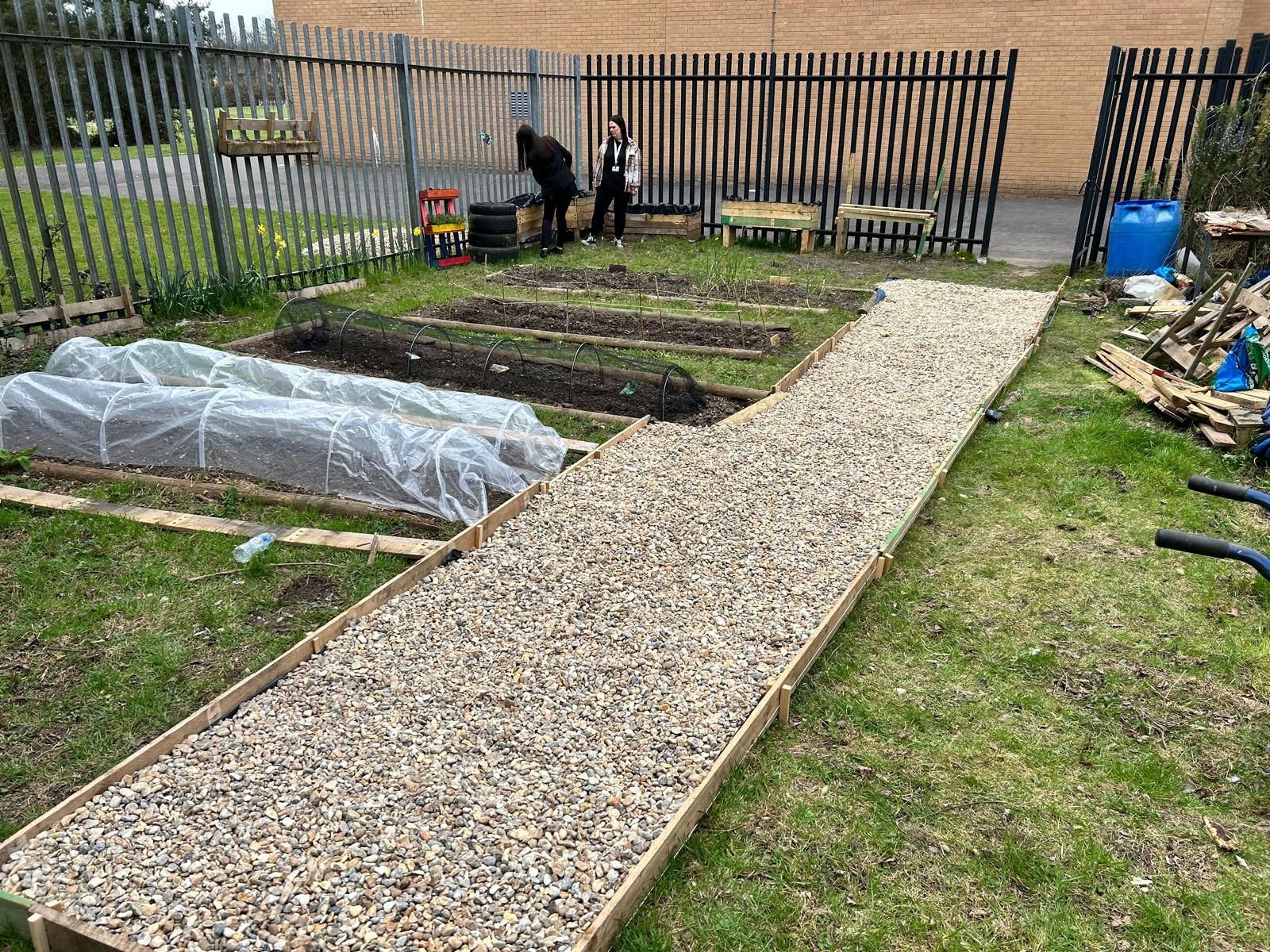 A man is working in a garden next to a gravel path.