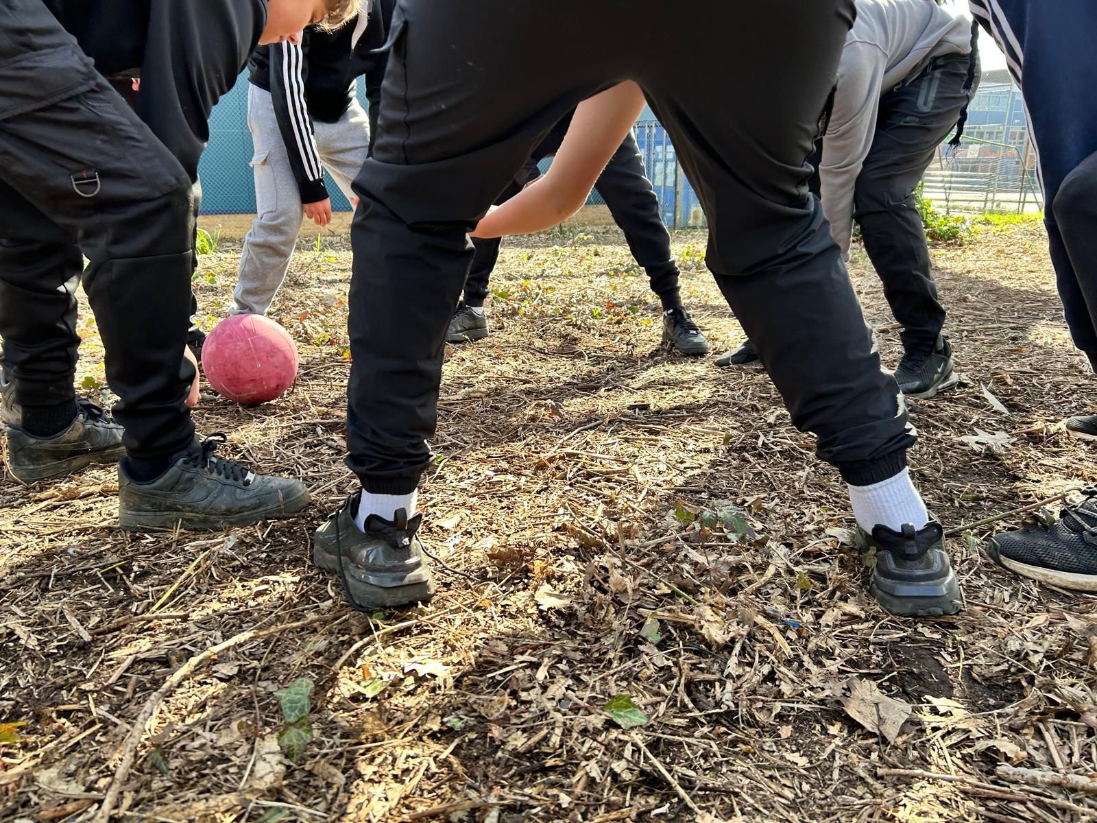 A group of people are standing around a ball on the ground.