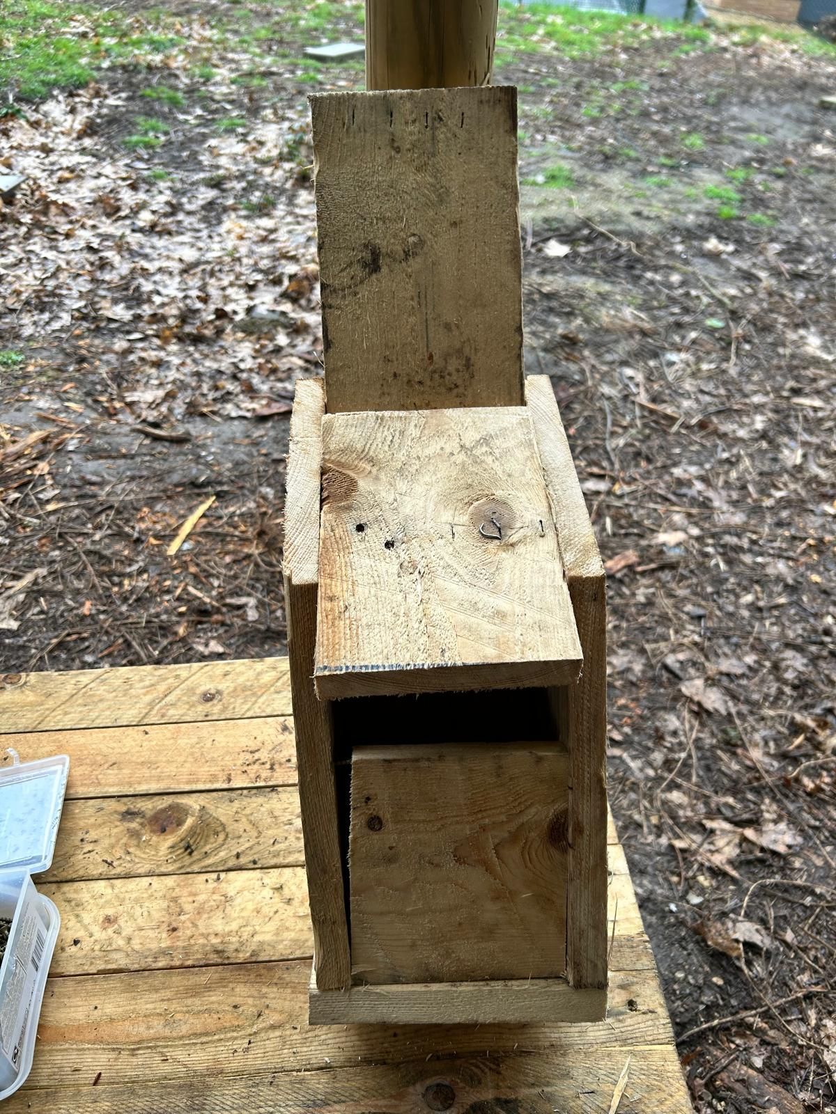 A wooden birdhouse is sitting on top of a wooden table.