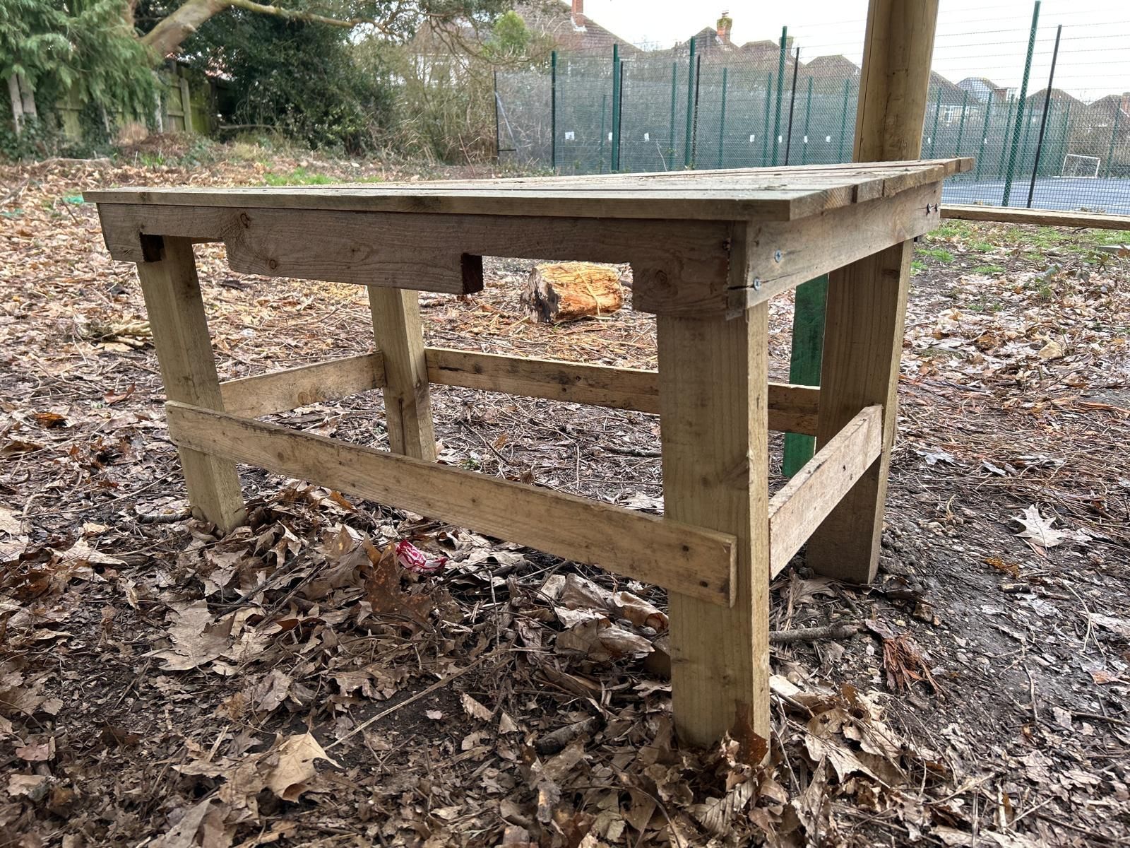 A wooden table is sitting on top of a pile of leaves.