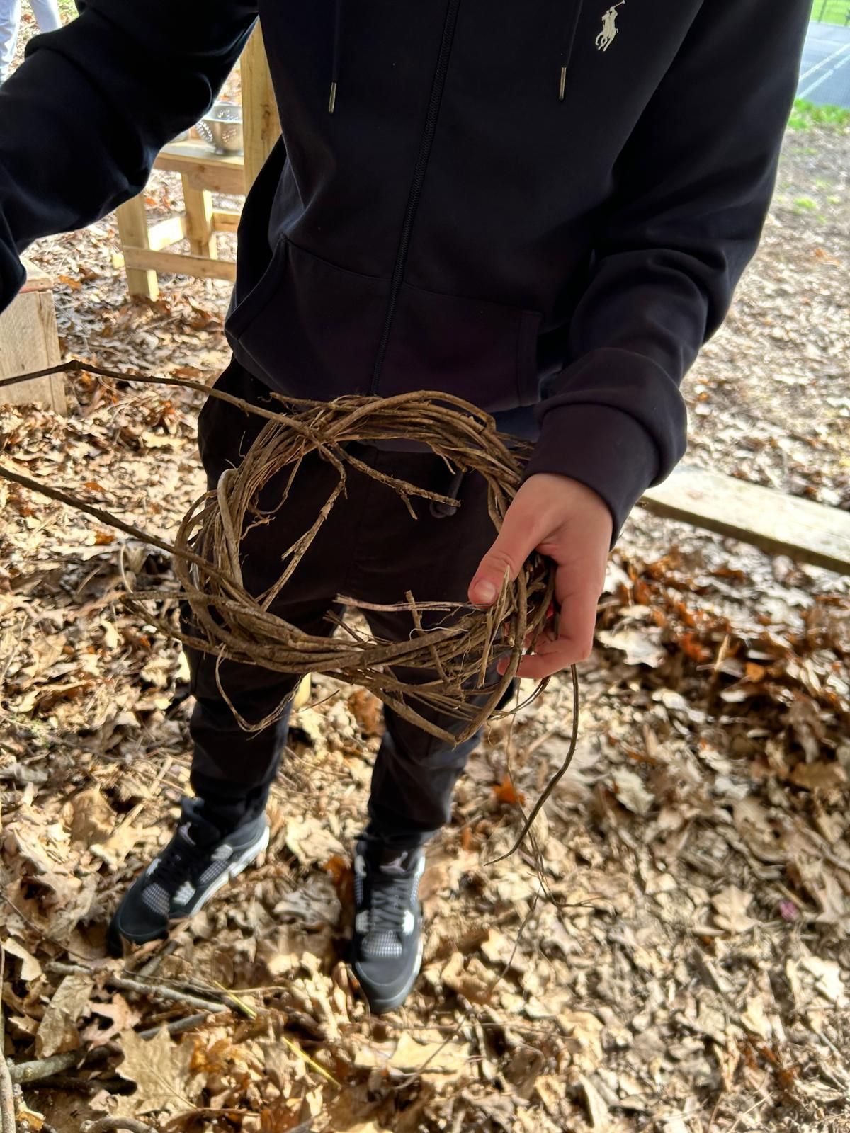 A person is holding a wreath of twigs in their hands.