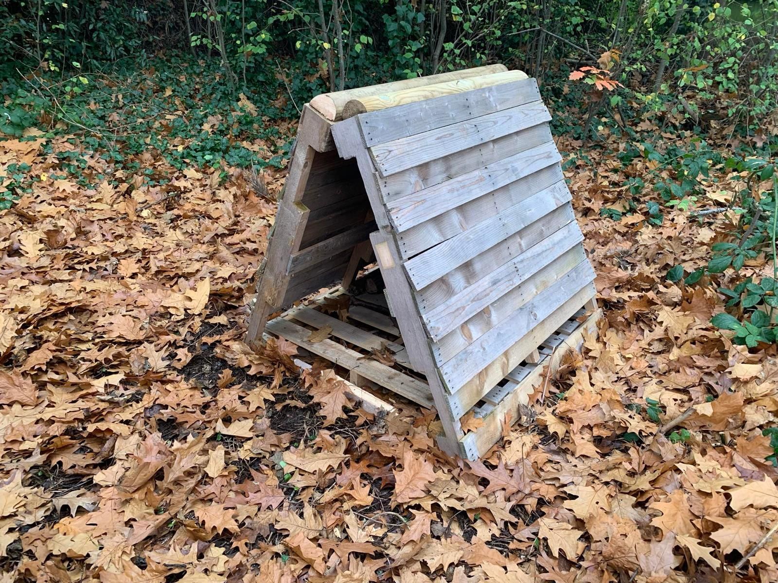 A small wooden structure is sitting on top of a pile of leaves.