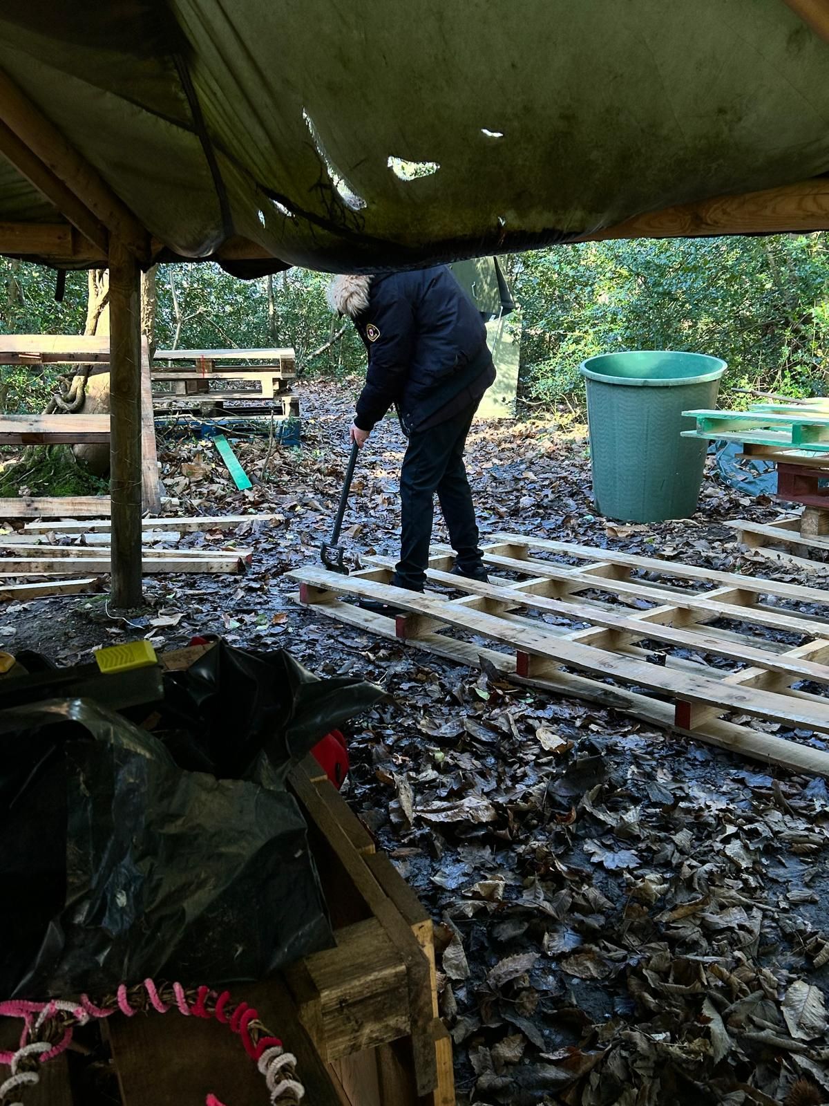 A man is standing on a pile of wooden pallets.