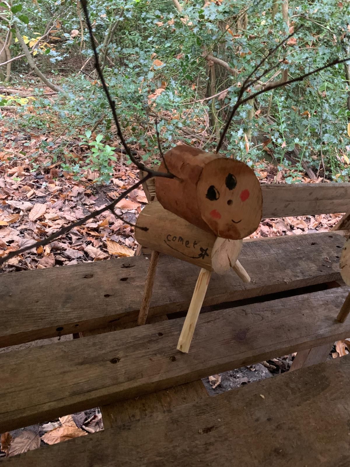 A wooden reindeer is sitting on a wooden bench.