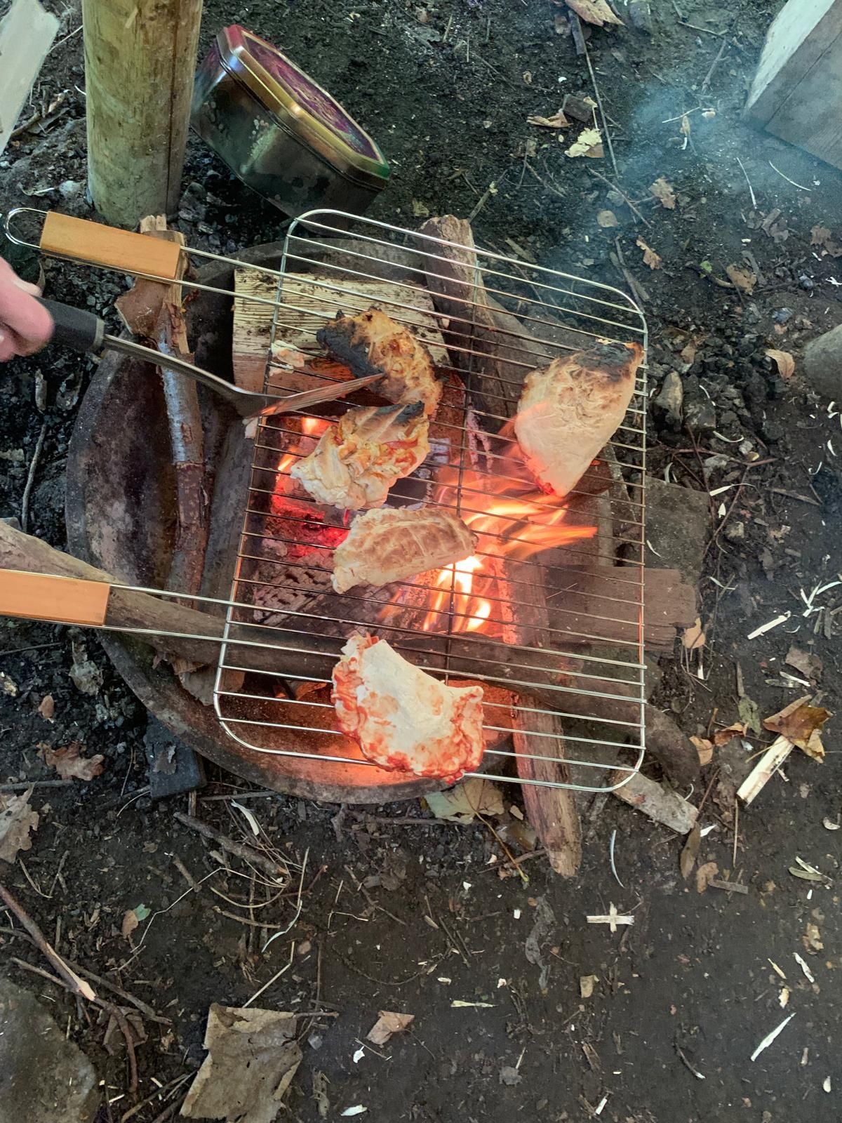 A person is cooking food on a grill over a fire.