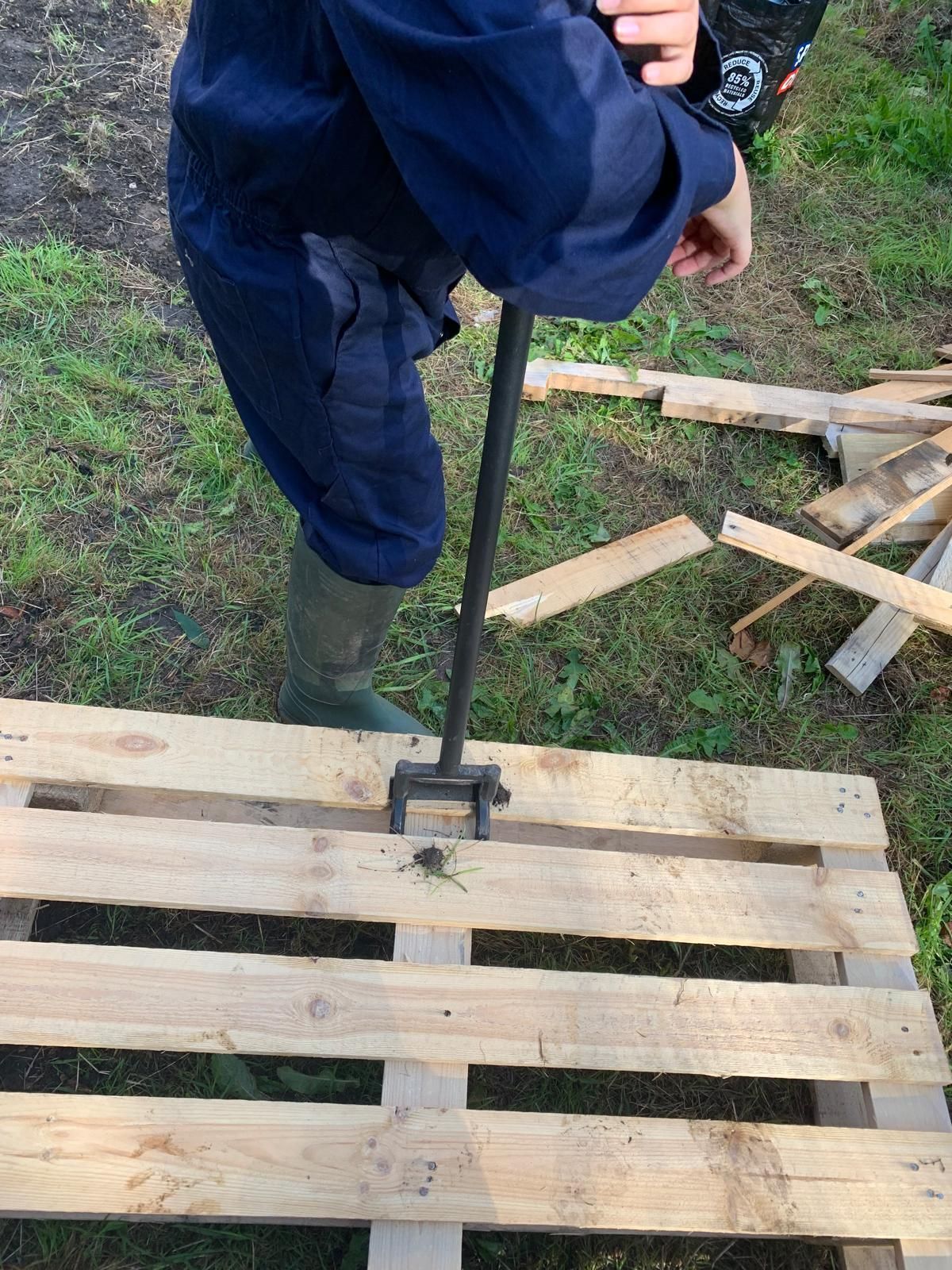 A person is using a tool to drill a hole in a wooden pallet.