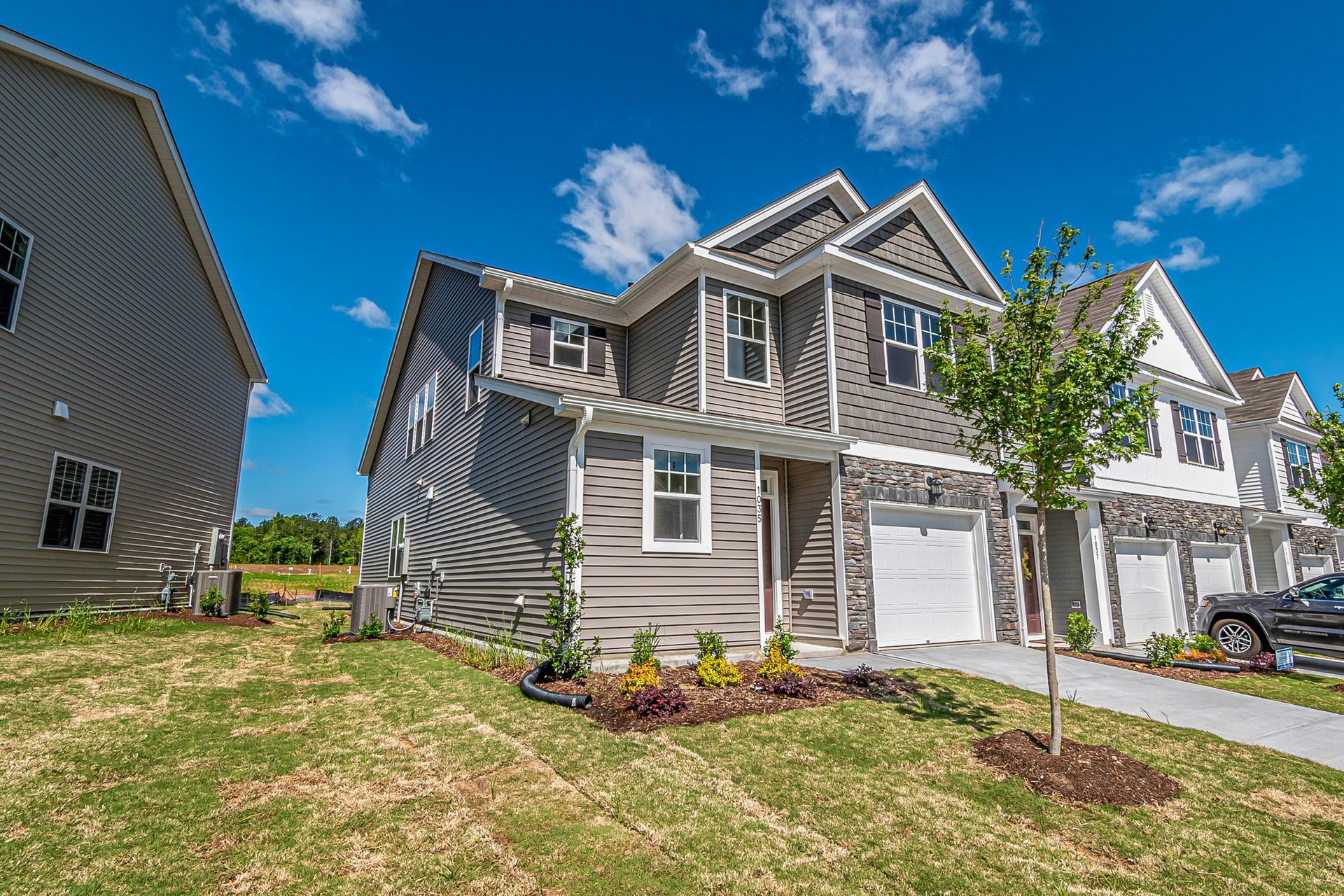 Row of gray townhomes with white garage doors 