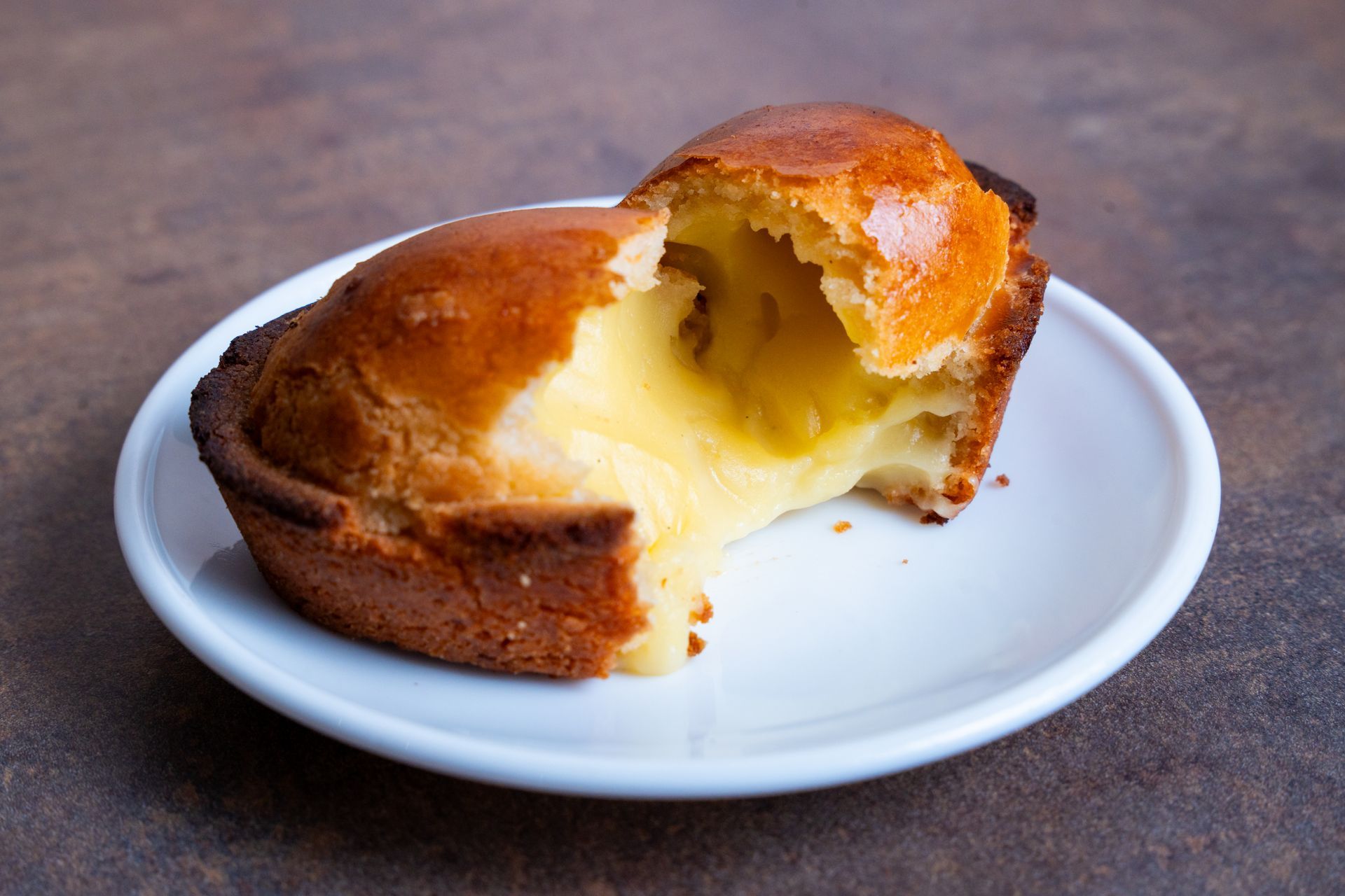 Una torta a fette, dorata e con un morbido ripieno giallo, adagiata su un piatto bianco.