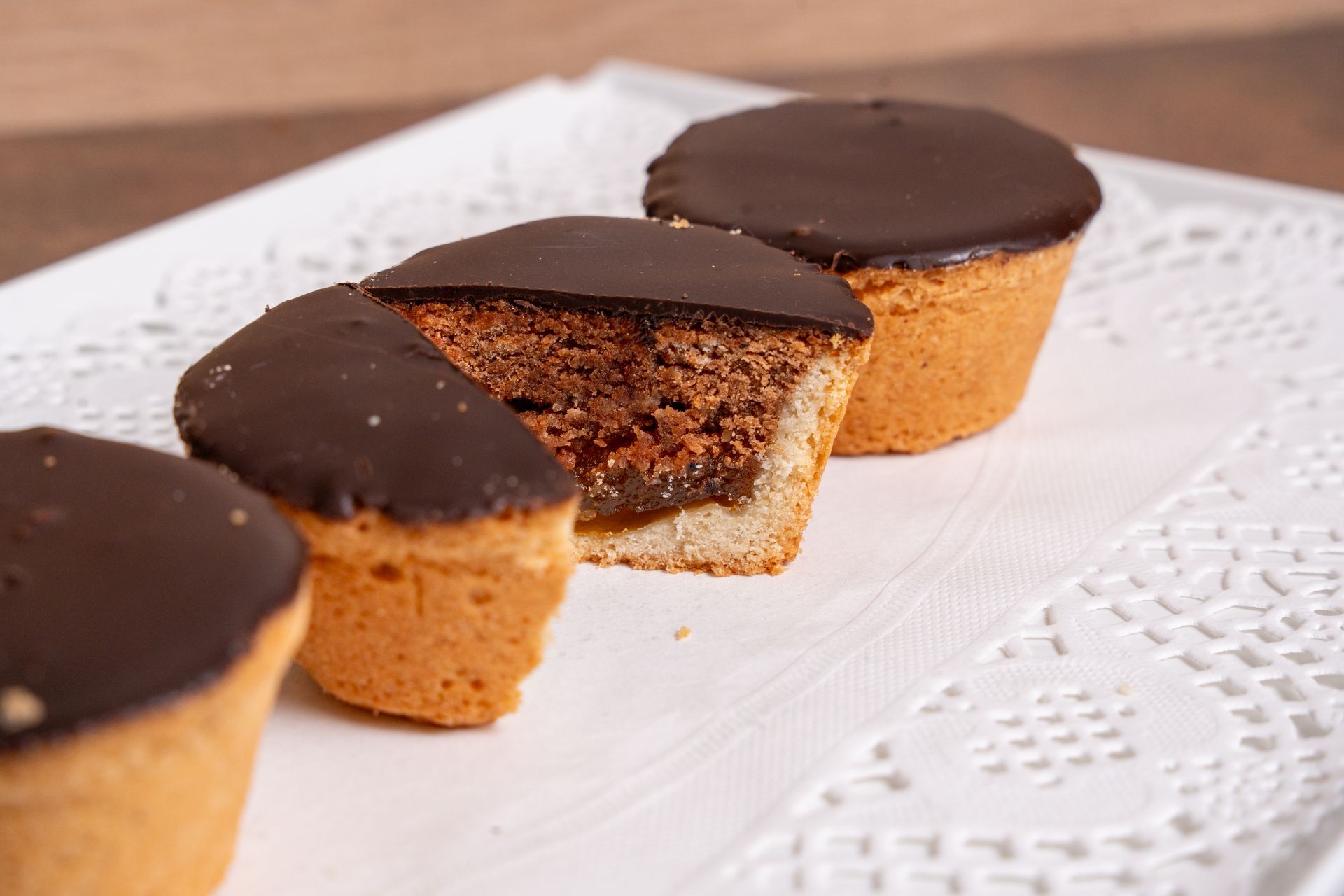 Cupcake ricoperti di cioccolato su un vassoio foderato di centrino bianco, uno dei quali tagliato a metà per mostrare l'interno.