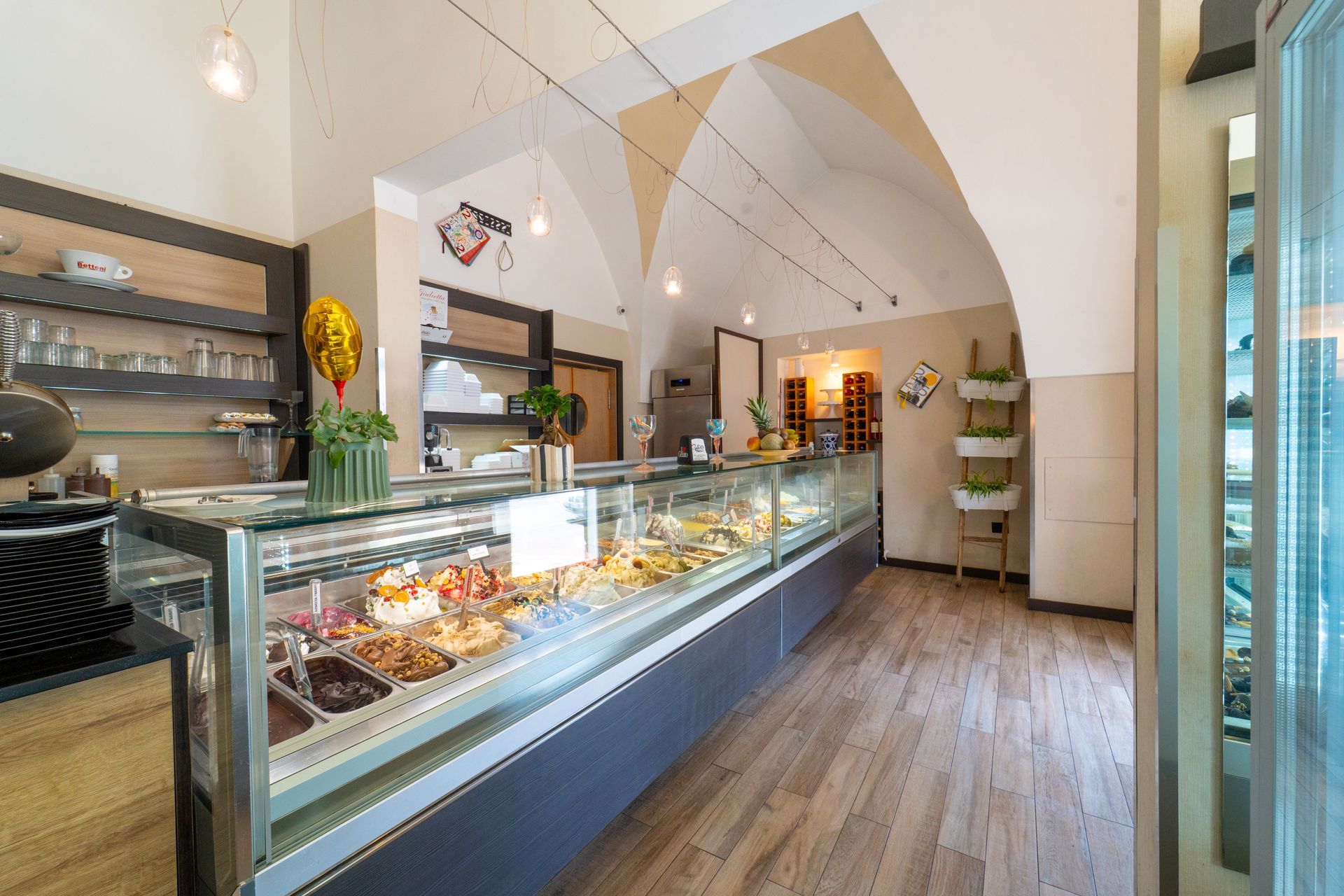 Interni moderni di una pasticceria con vetrine in vetro per i dolci e pavimenti in legno caldo.