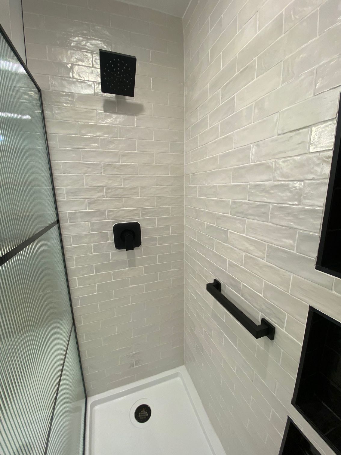 Custom tile shower with fixed glass shower door and matte black fixtures