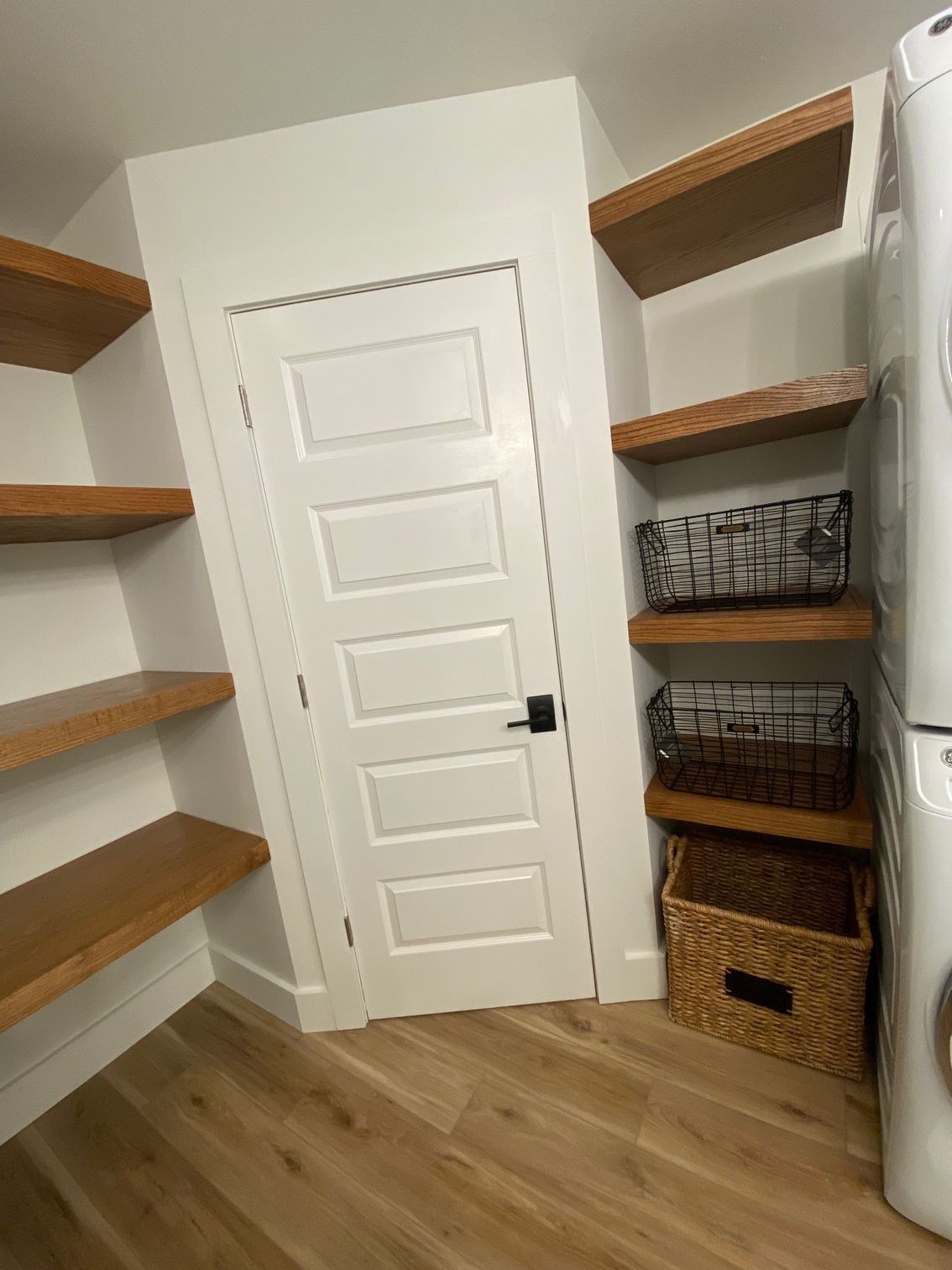 Angled utility room door with custom floating shelves to accommodate larger bath and laundry space