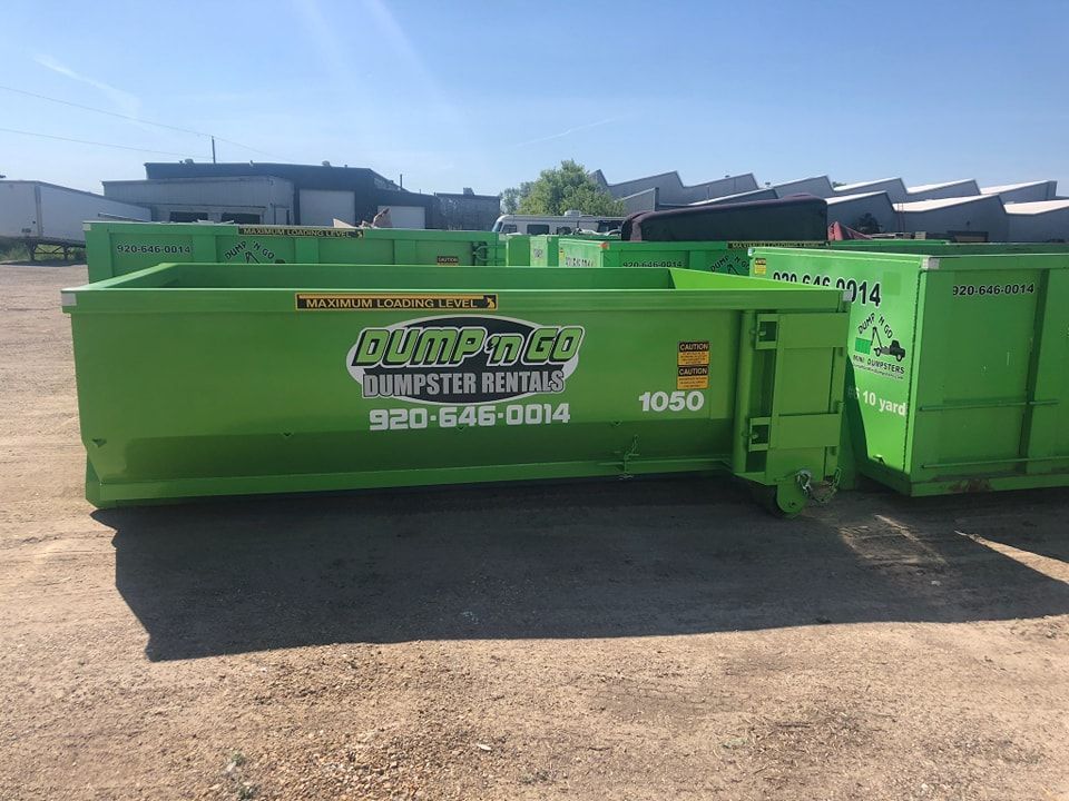 Green dumpster with "Dump-N-Go Dumpster Rentals" logo and phone number, sitting in a paved lot.