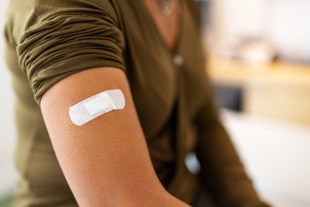 A woman has a bandage on her arm after getting a vaccine.