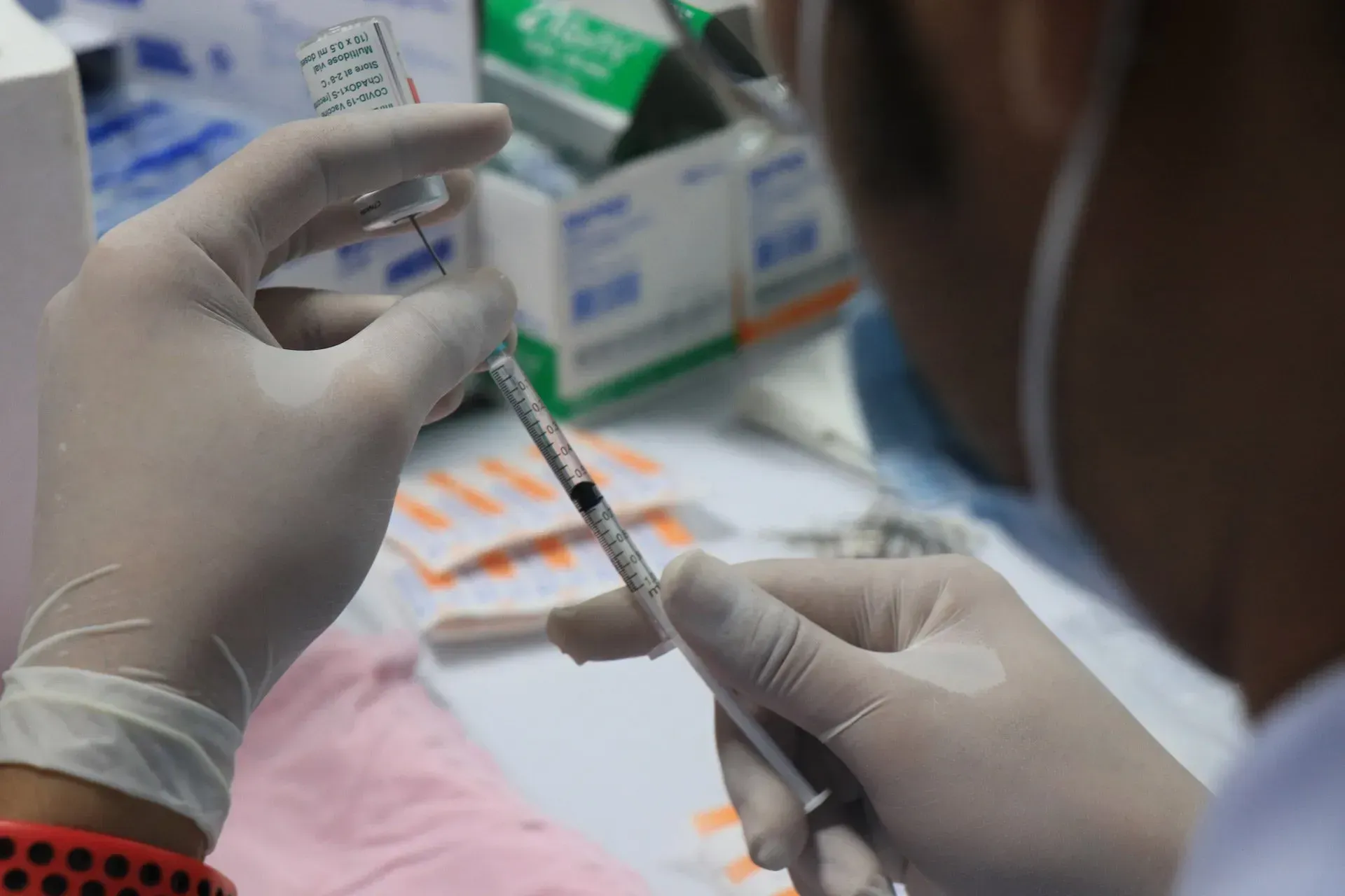 A person is holding a syringe and a bottle of vaccine. A person is holding a syringe and a bottle of vaccine.