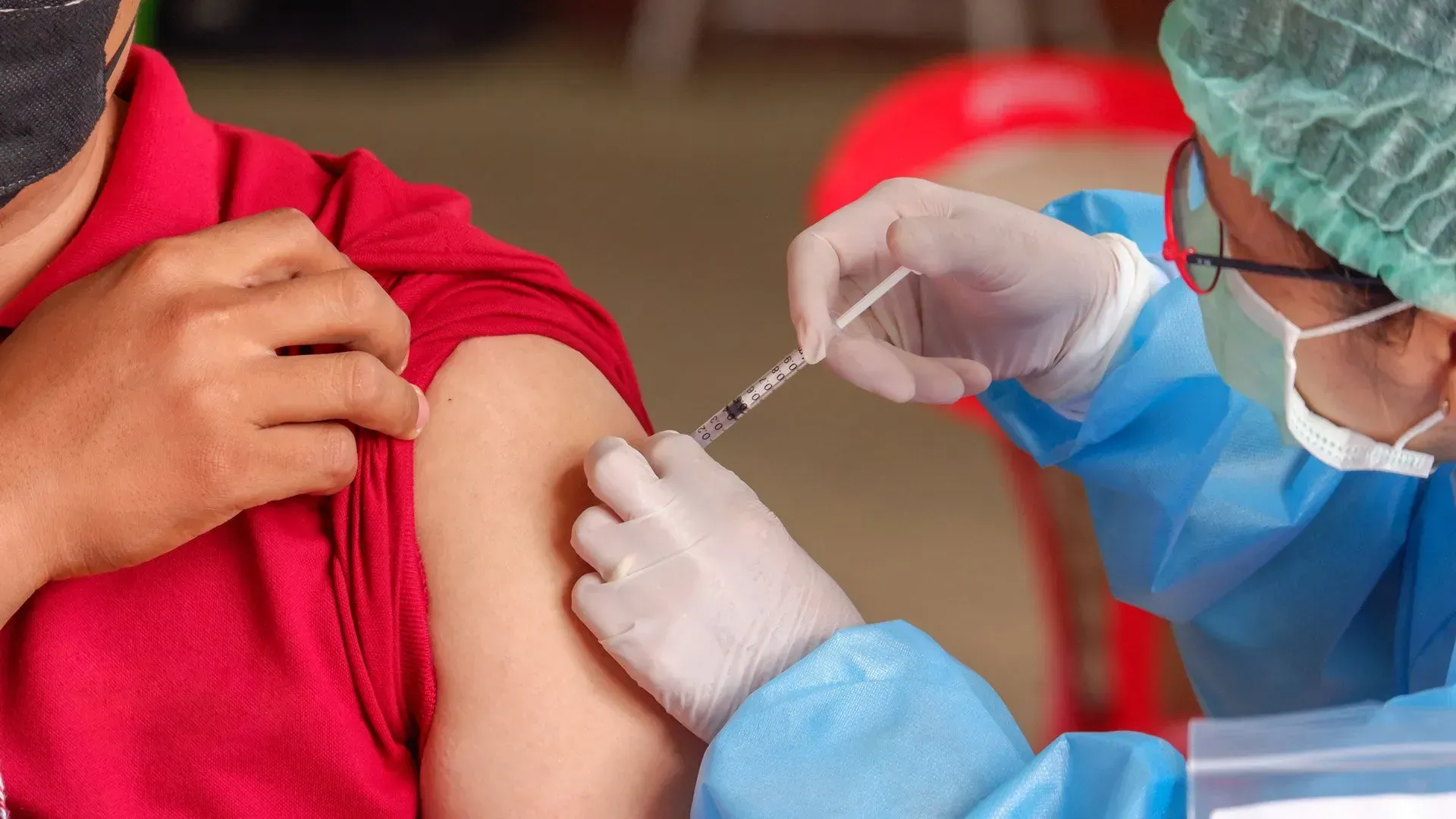A person is getting a vaccine in their arm. A person is getting a vaccine in their arm.