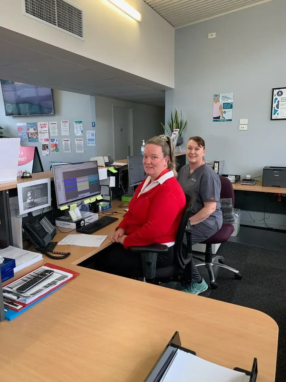 Two women are sitting at desks in an office. Two women are sitting at desks in an office.