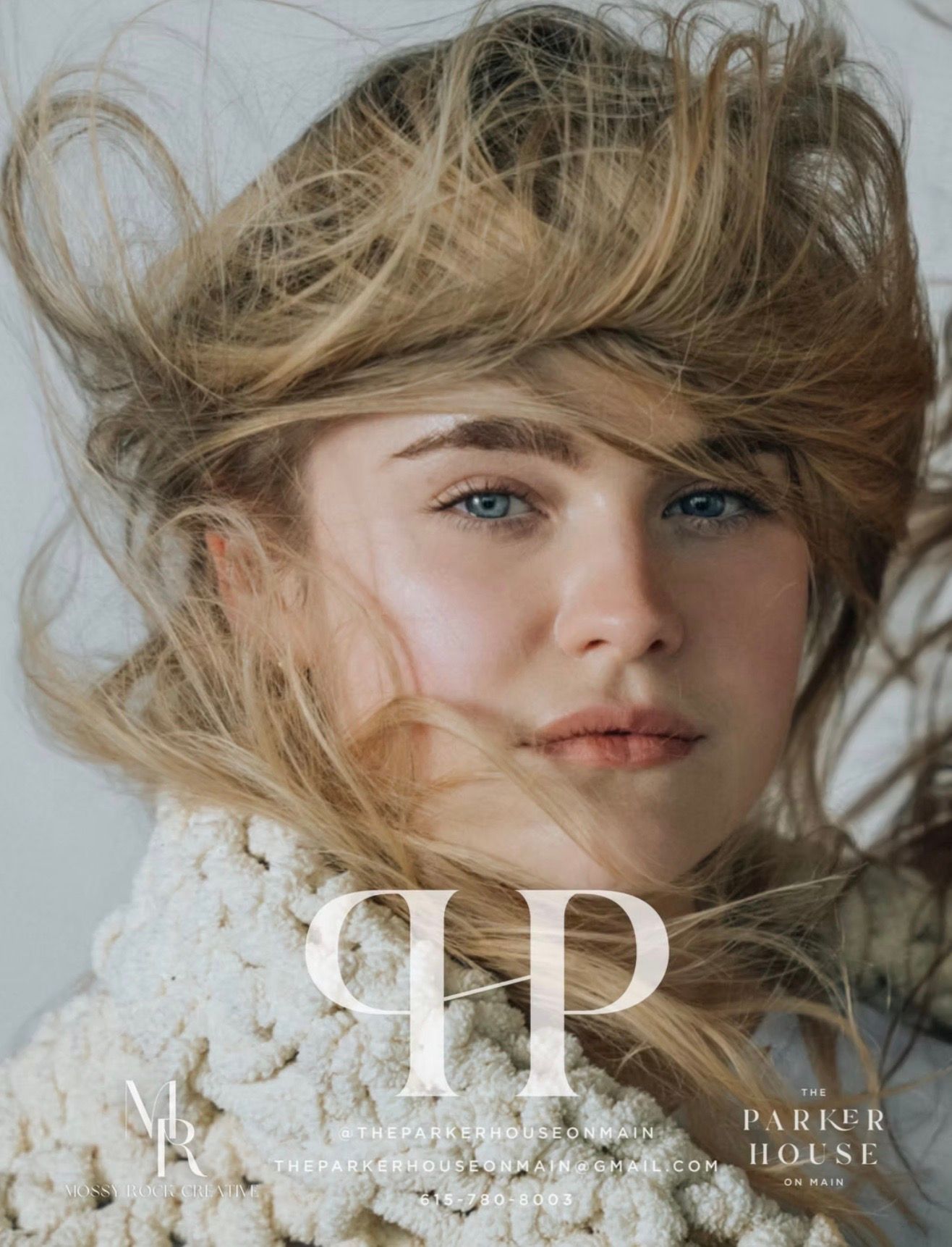 Blonde woman with tousled hair and blue eyes, wearing a cream-colored shawl. White background with 