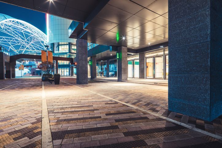 Courtyard of a sandstone building with windows and chimneys, green grass, and a cloudy sky.