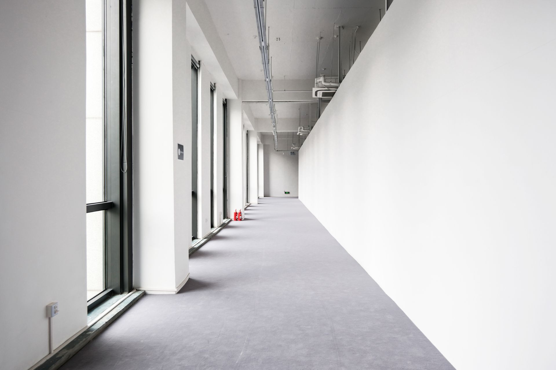 Empty room with gray carpet, white walls, small window, and doorway to a bathroom.
