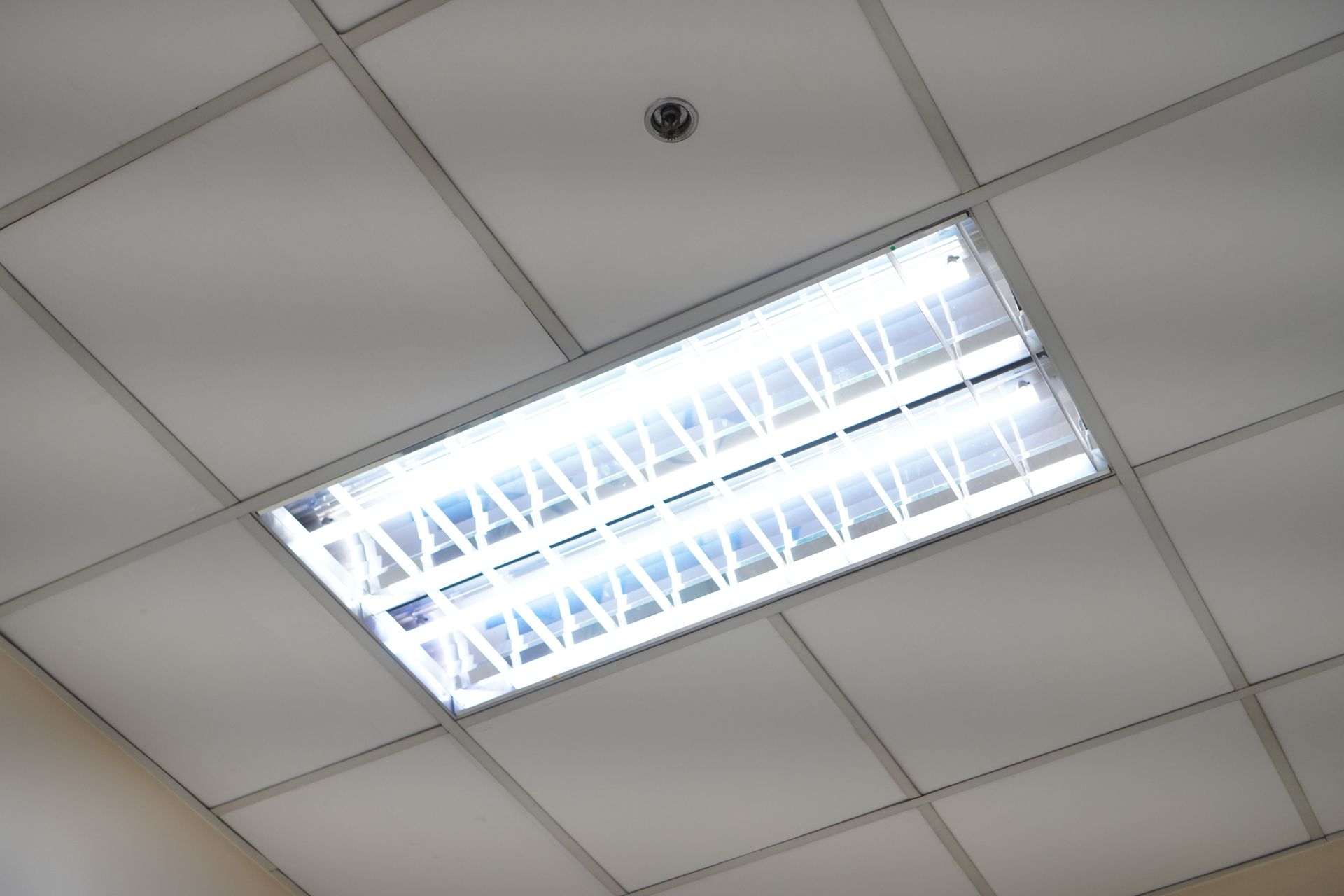 Person wiring a smoke detector on a white ceiling.