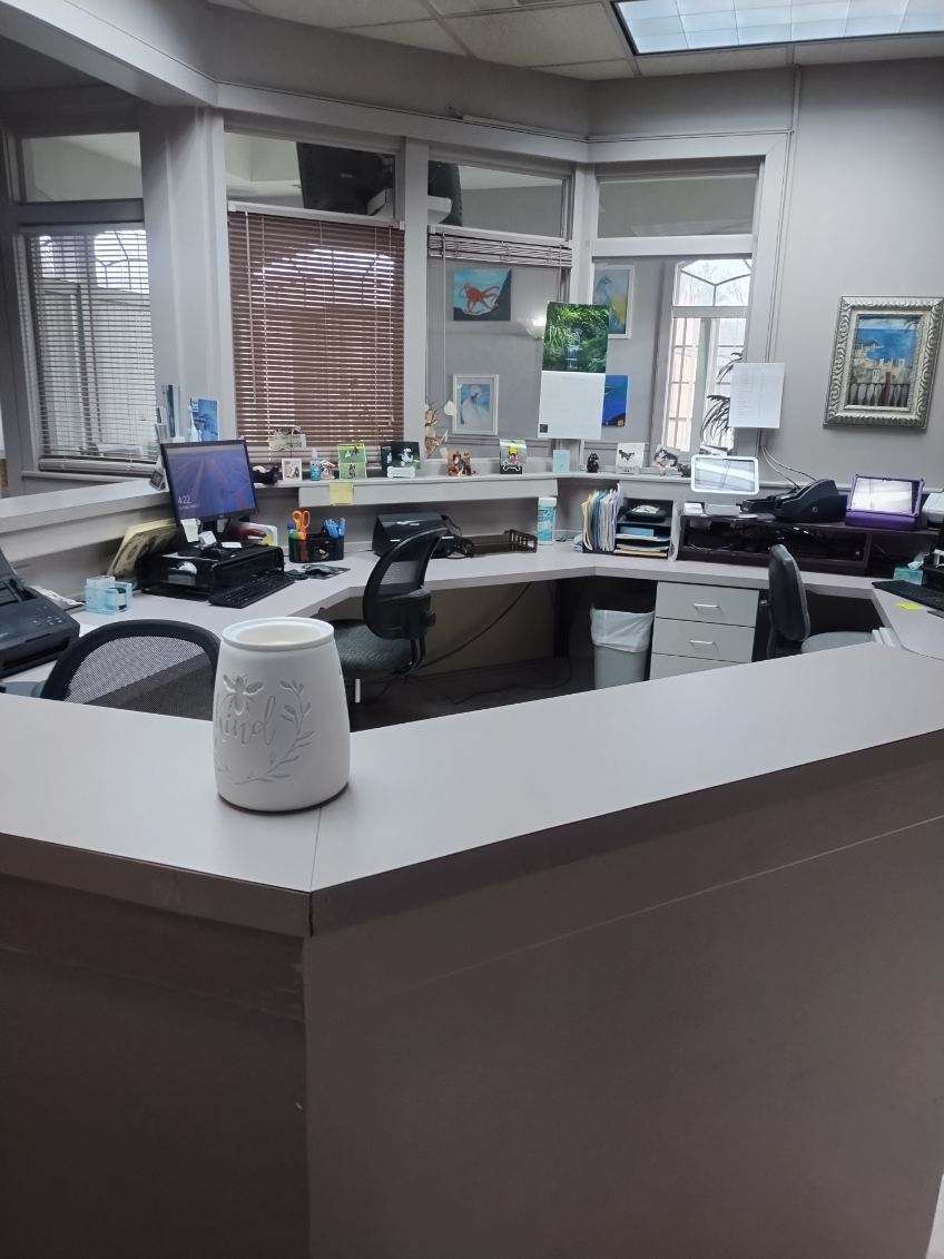 A reception area in a dental office with a desk and chairs.