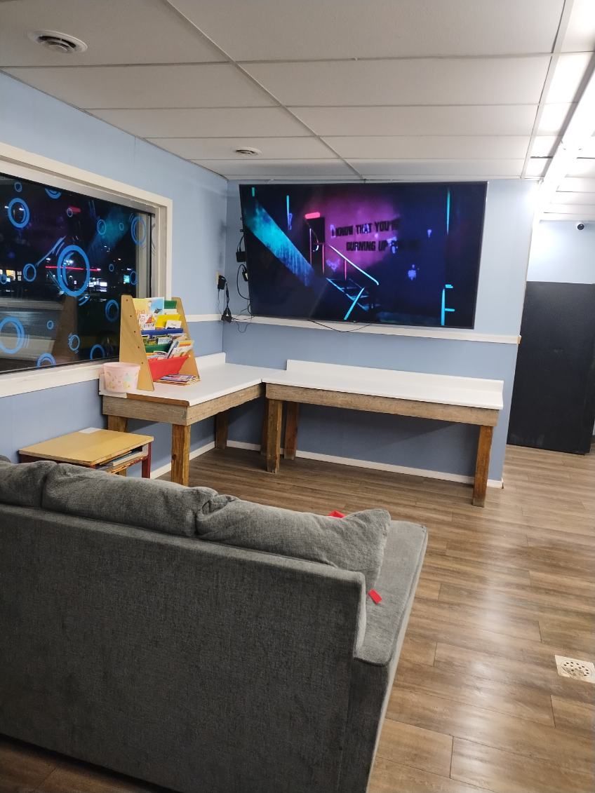 A living room with a couch , table and a large screen on the wall.
