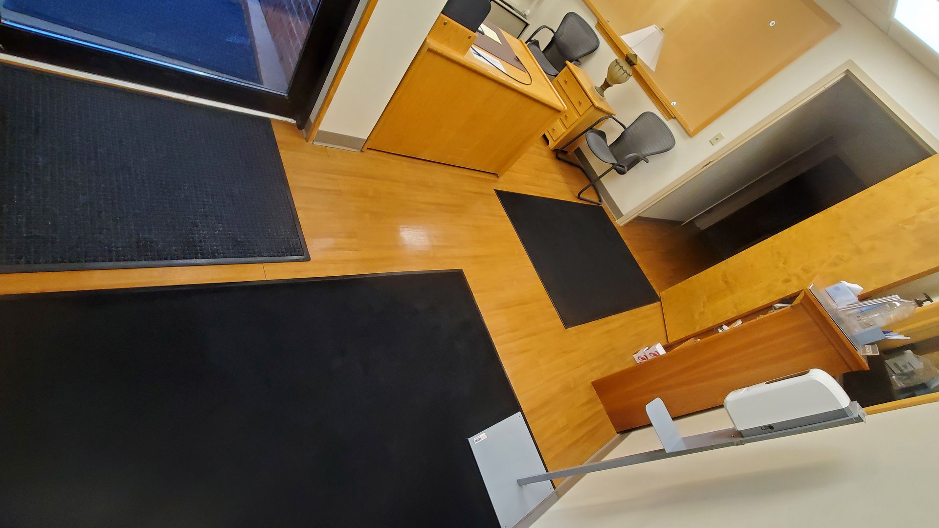 A room with wooden floors and black mats on the floor