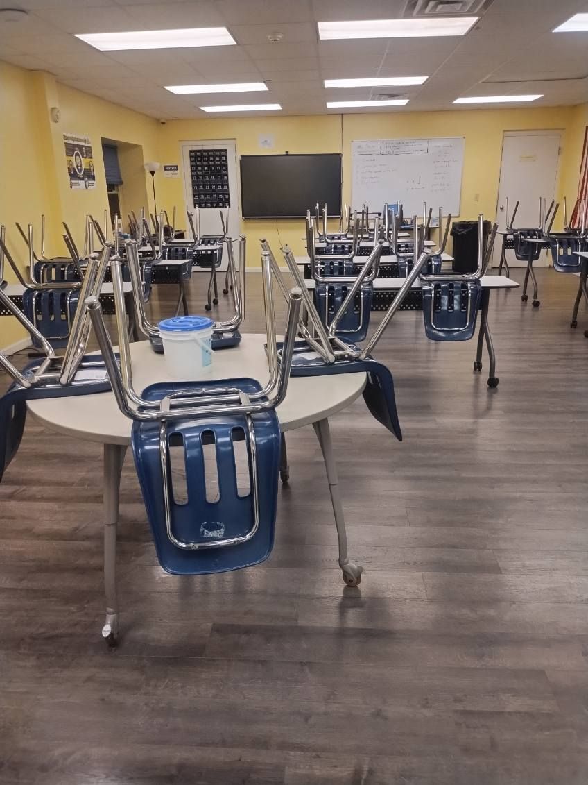 A classroom with tables and chairs that are empty.