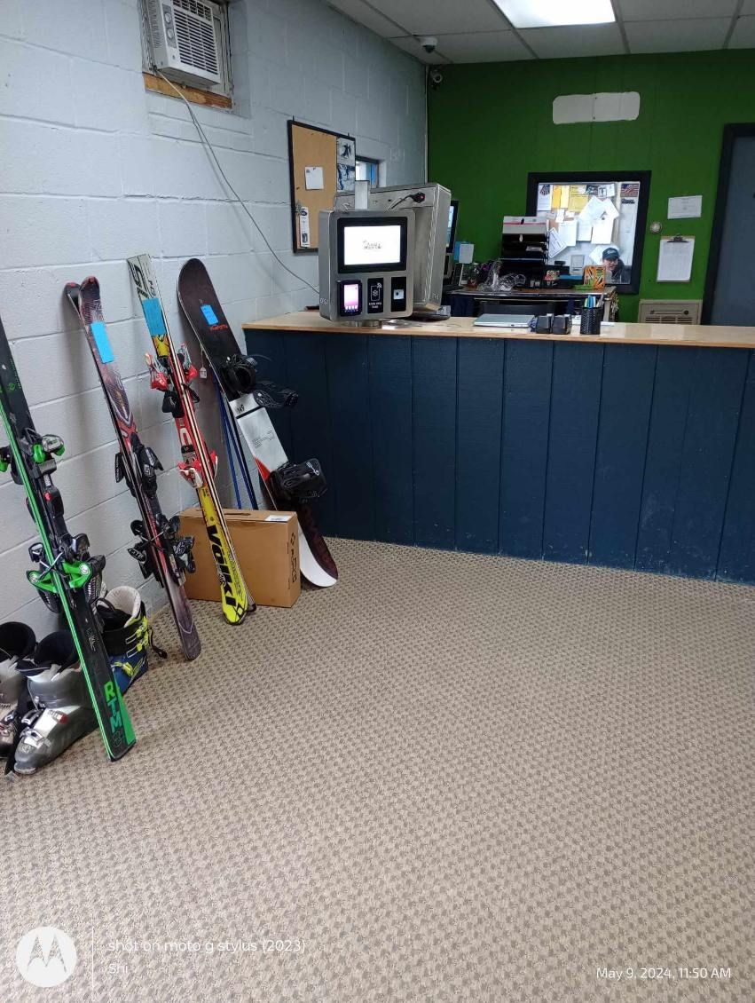A bunch of skis and snowboards are sitting on the floor in a room.