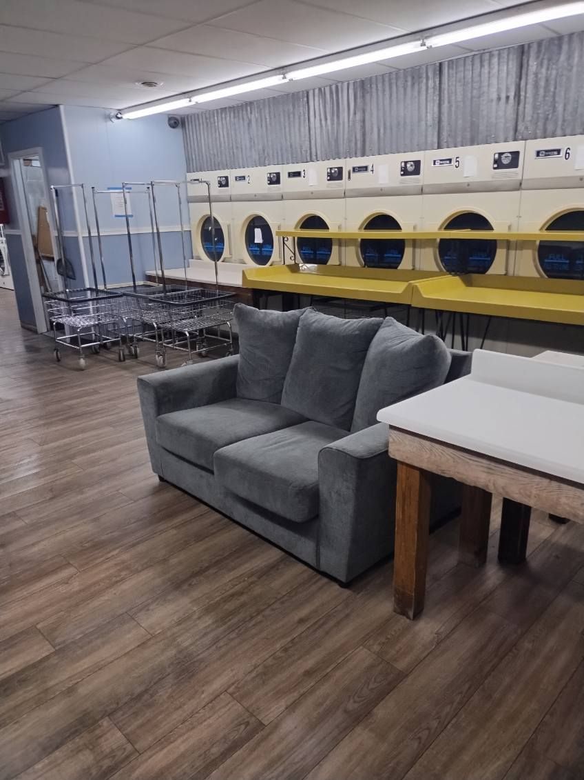 A couch is sitting in a laundromat next to a table.