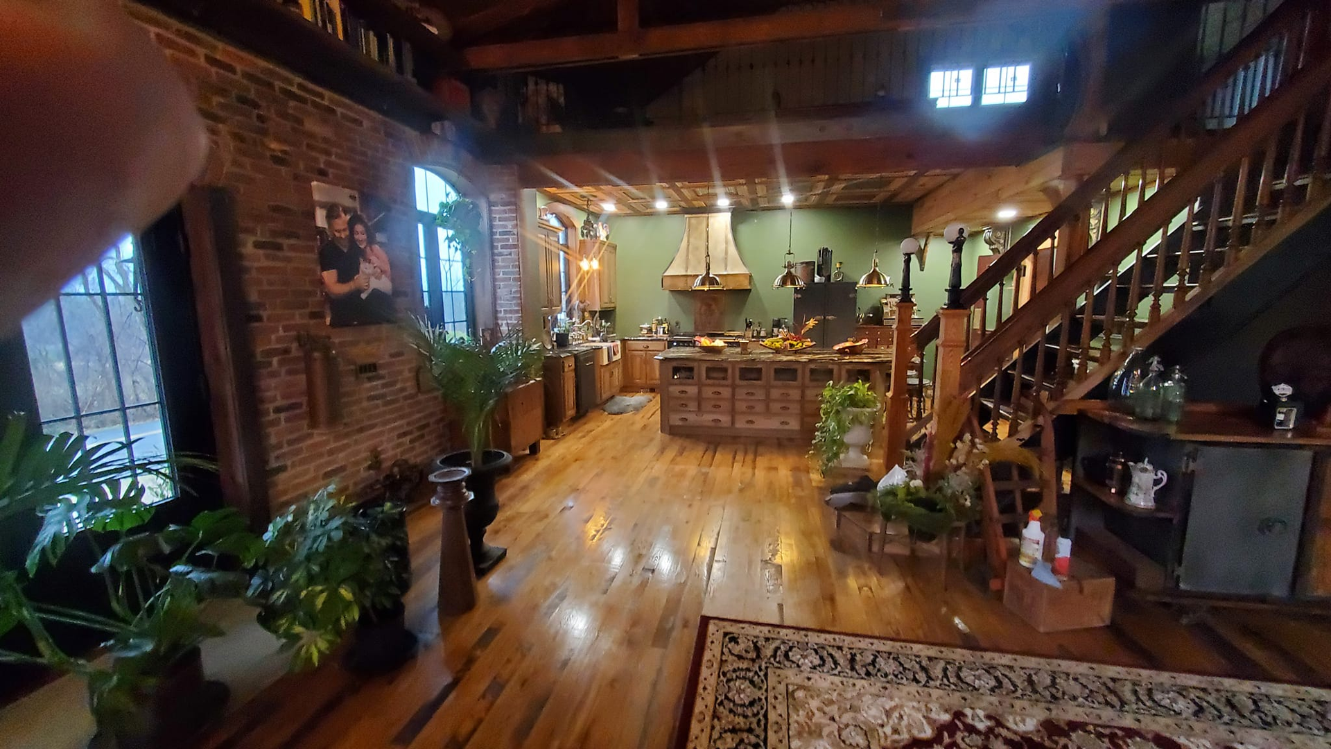 A large room with wooden floors and stairs in a house.