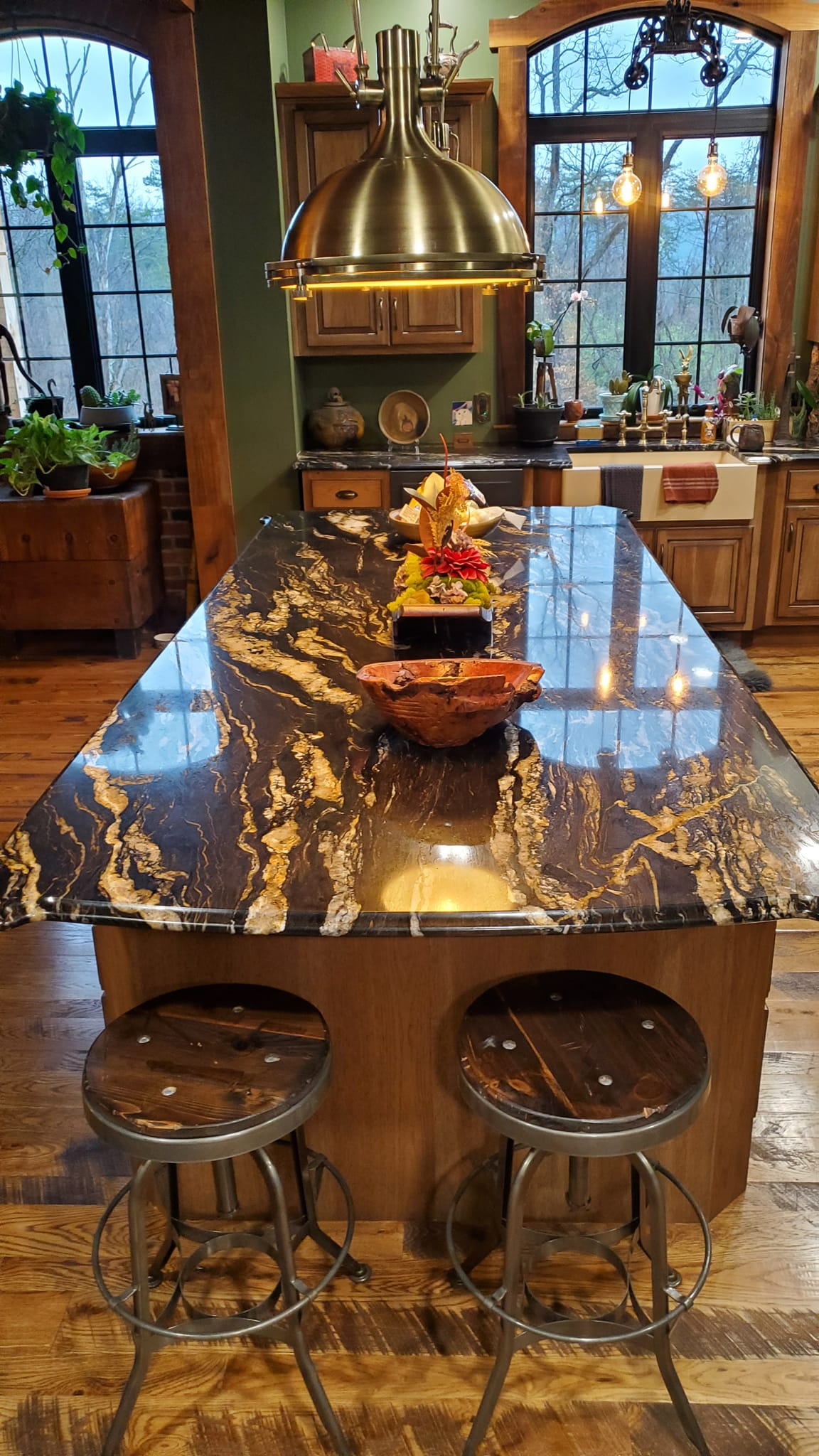 A kitchen with a large granite counter top and stools.