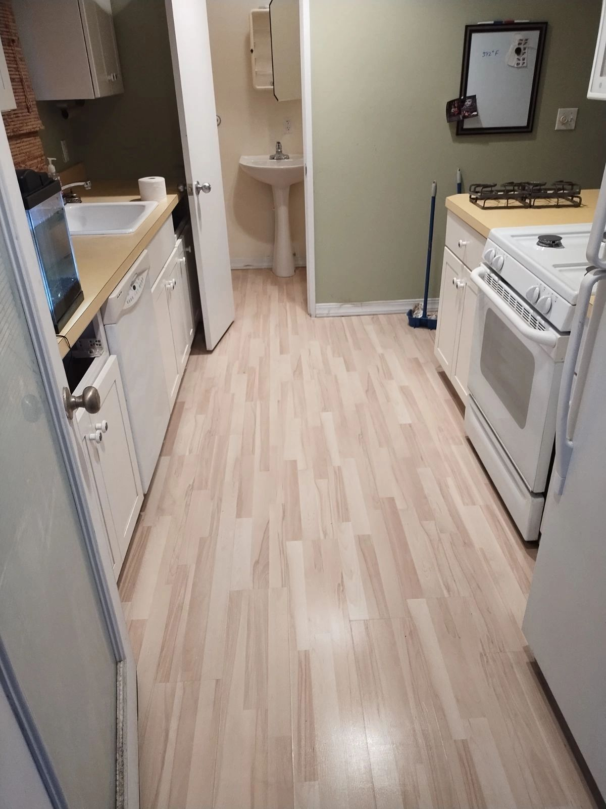 A kitchen with hardwood floors and white appliances