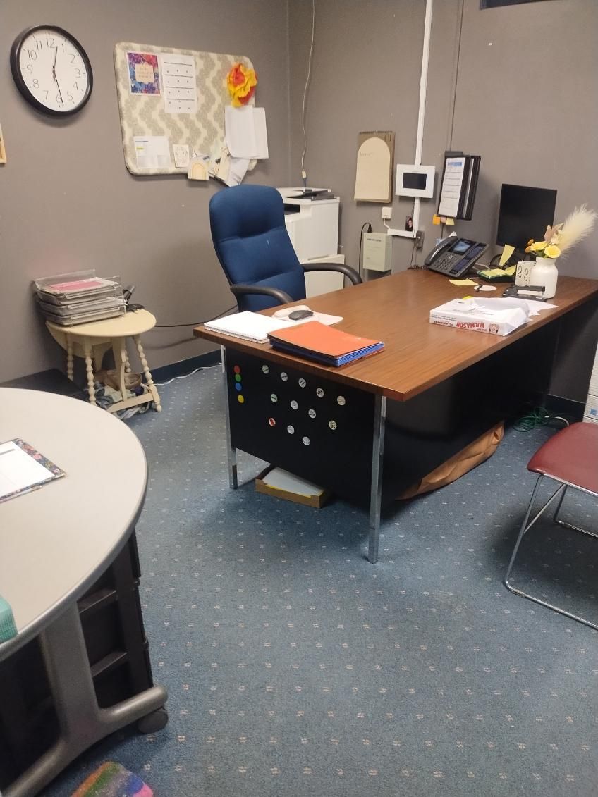 An office with a desk and chair and a clock on the wall