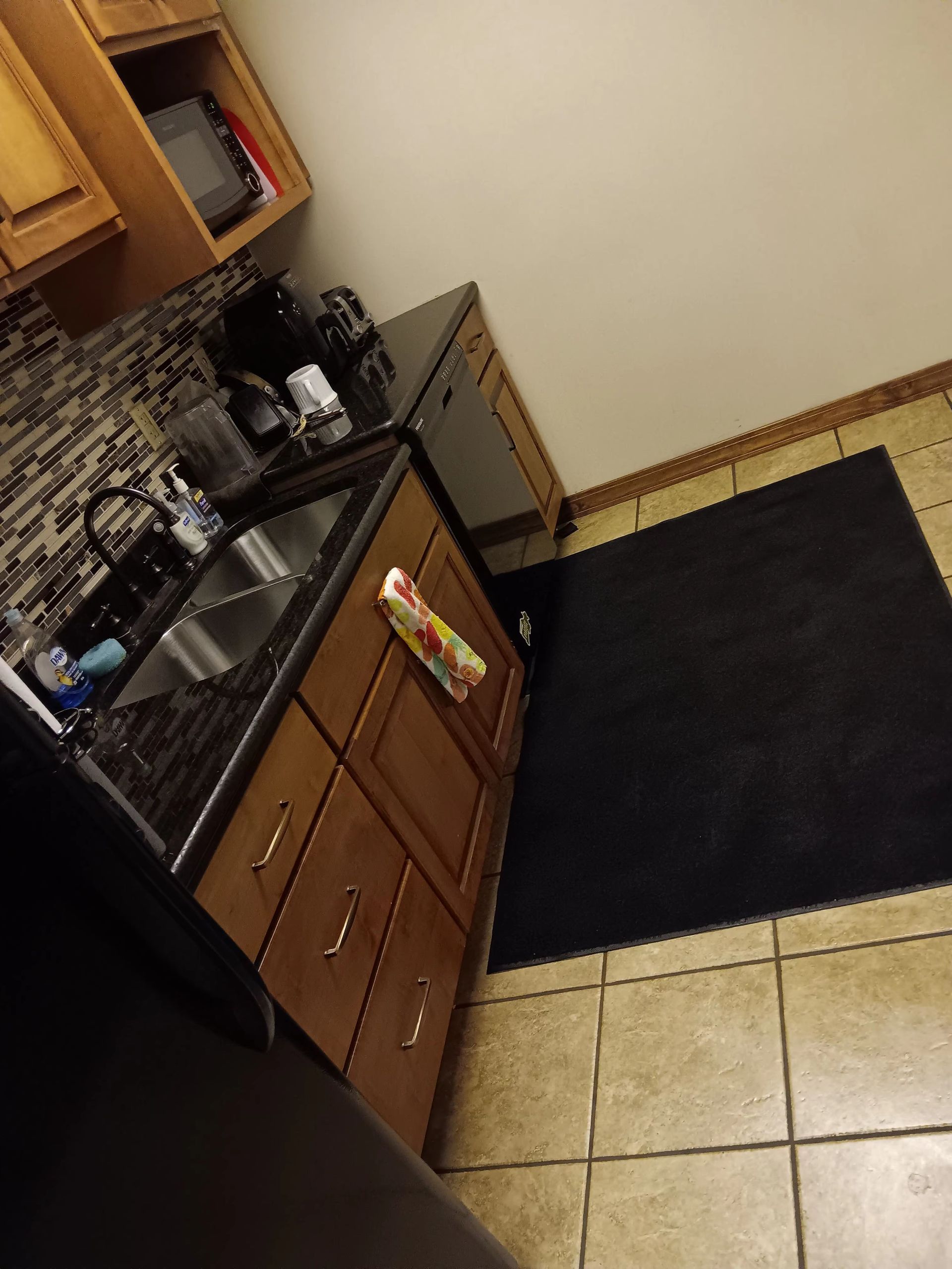 A kitchen with a black rug on the floor