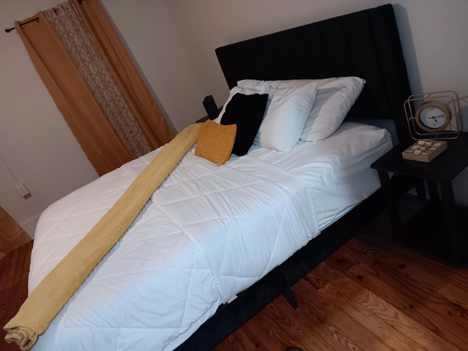 A bedroom with a bed and a clock on the nightstand