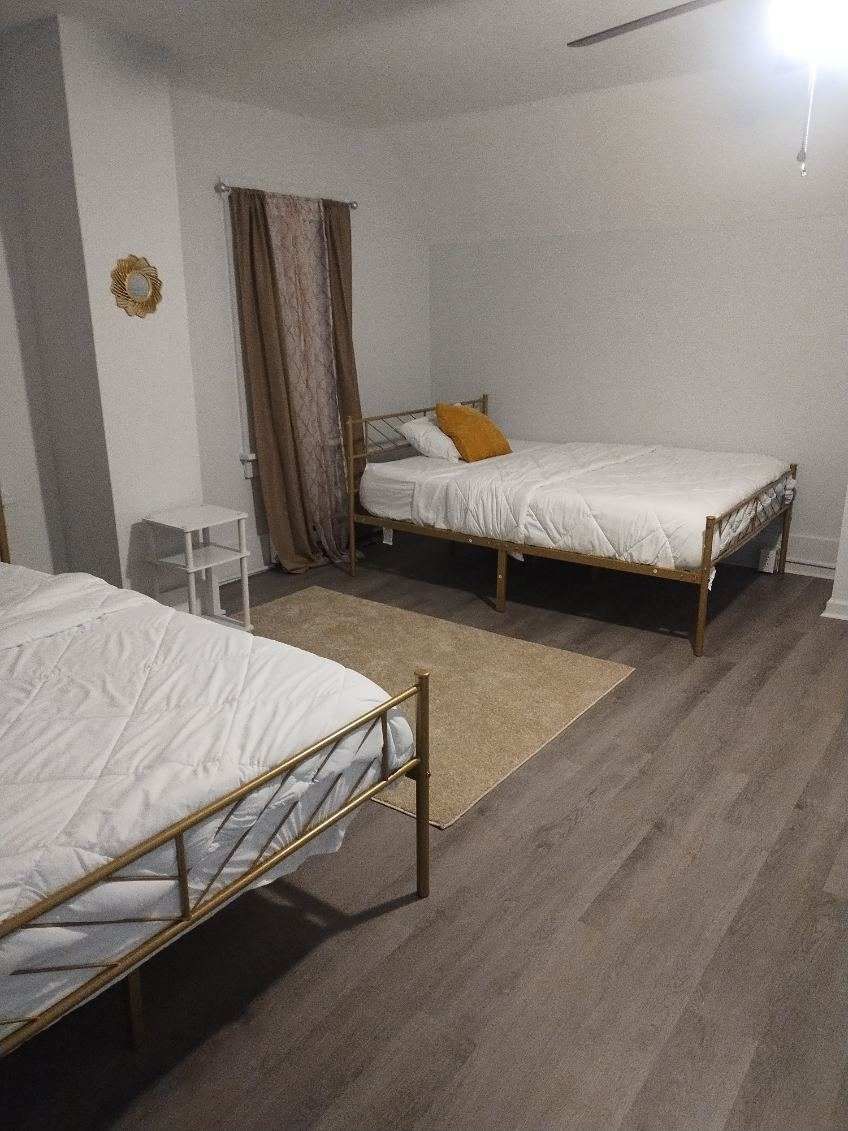 A bedroom with two beds and a rug on the floor.