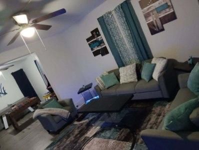 A living room with a couch , chair , coffee table and ceiling fan.