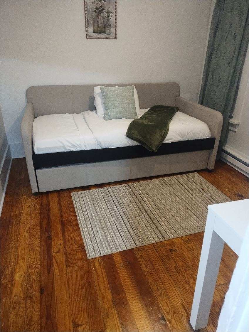 There is a couch in the middle of the room with a rug on the floor.