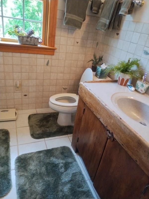 A bathroom with a toilet , sink , and window.