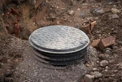 A manhole cover is sitting on top of a pile of dirt.