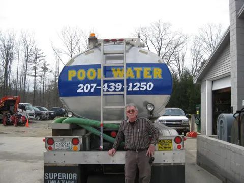 A man stands in front of a pool water truck.