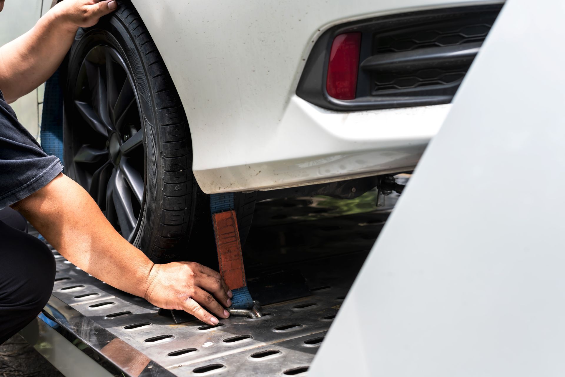 Professional securing a vehicle for transport using a reliable car towing service flatbed. Professional securing a vehicle for transport using a reliable car towing service flatbed.