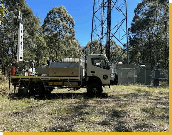 A man is sitting in front of a machine in a park.
