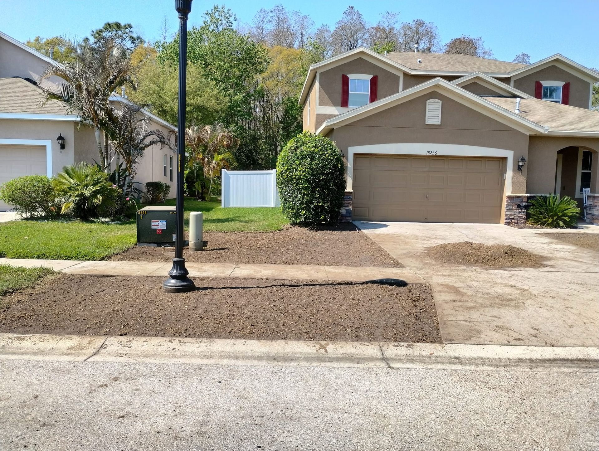 Houses with freshly mulched front yards, street view.