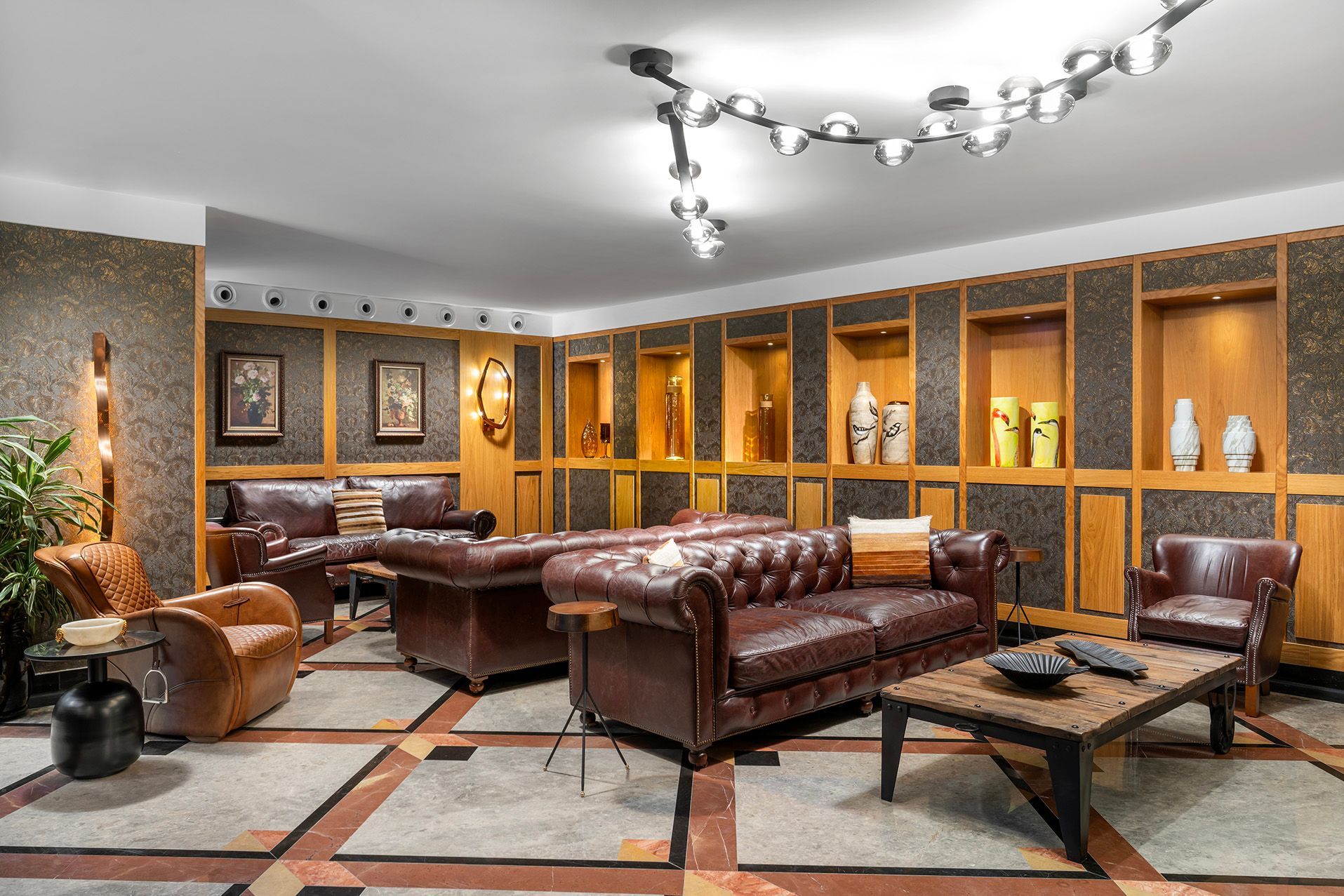 Modern lounge with leather sofas, wood-paneled walls, a bar, and geometric tile flooring