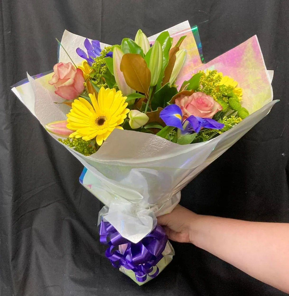 A Person is Holding a Bouquet of Flowers Wrapped in White Paper — Wingham Nursery and Florist PTY Ltd In Wingham, NSW